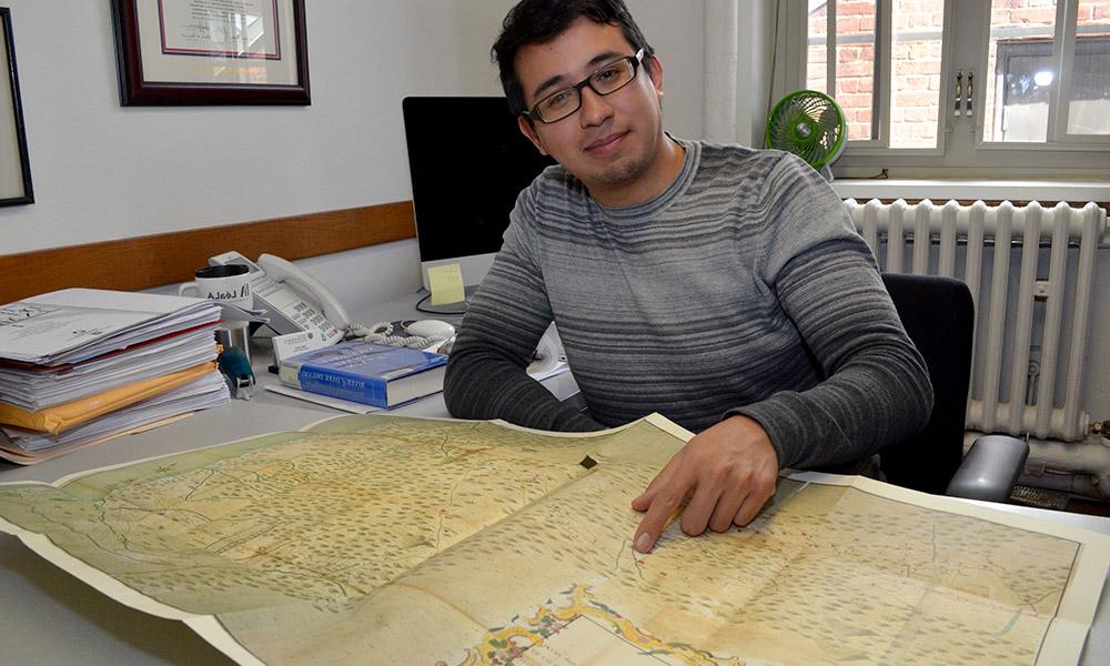 Pablo Sierra in his office, points to map